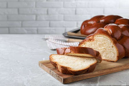 Cut homemade braided bread on gray table, space for text. Traditional Shabbat challahの写真素材