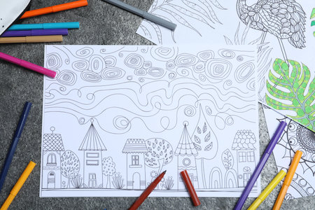 Antistress coloring pages and felt tip pens on gray table, flat lay