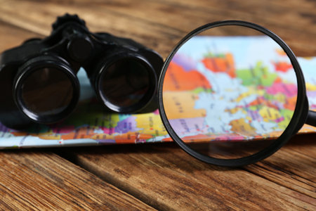 Magnifying glass, modern binoculars and map on wooden table, closeupの写真素材