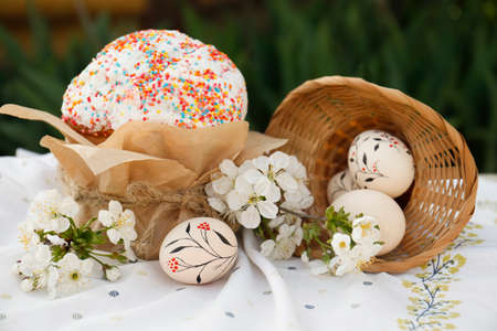Eggs with floral ornaments and kulich for Easter near blossoming tree twigs on clothの写真素材