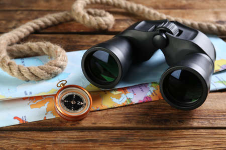 Modern binoculars, map, compass and rope on wooden table, closeupの写真素材