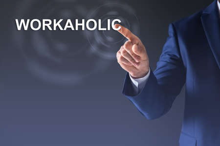 Man pointing at word Workaholic on virtual screen against dark background
