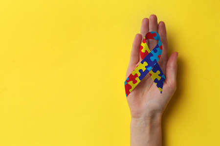 World Autism Awareness Day. Woman with colorful puzzle ribbon on yellow background, top view with space for textの写真素材