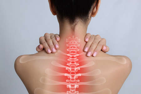 Woman suffering from pain in neck on light gray background, closeupの写真素材