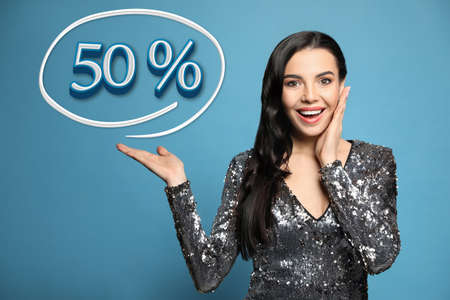 Surprised woman pointing at illustration of fifty percent on light blue background. special promotionの写真素材