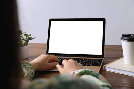 Woman working on laptop at wooden table, closeup. Mockup for design