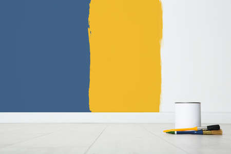 Decorator's tools on wooden floor near white wall with samples of different paints indoorsの写真素材
