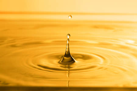 Splash of golden oily liquid with drops as background, closeupの写真素材