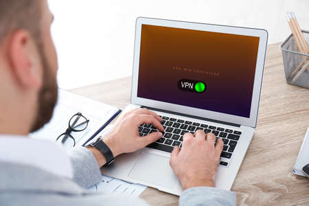 Man using laptop with switched on VPN at table, closeup