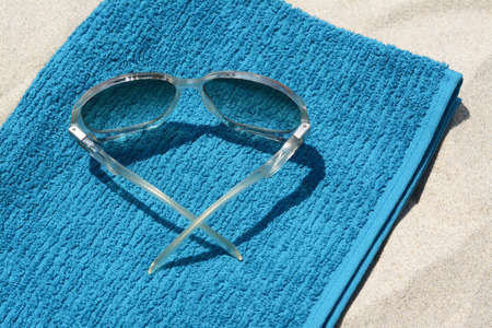 Soft blue towel and sunglasses on sandy beach, closeupの写真素材