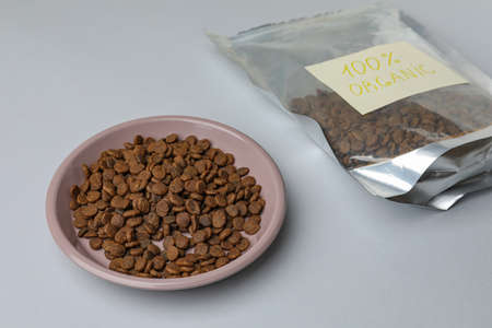 Plate and pack of organic kibble on light background