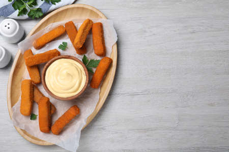 Delicious chicken nuggets and cheese sauce with parsley on white wooden table, flat lay. Space for...