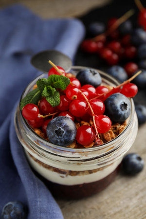 Delicious yogurt parfait with fresh berries and mint on wooden table, closeupの写真素材