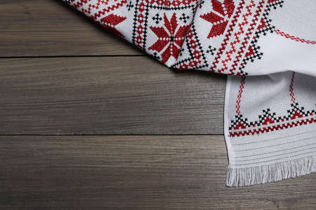Beautiful rushnyk on wooden table, top view with space for text. Ukrainian national embroidery