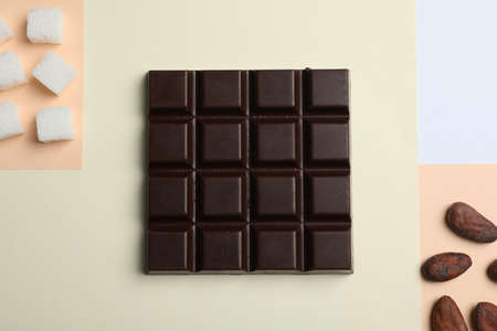 Delicious dark chocolate bar, refined sugar and cocoa beans on color background, flat layの写真素材