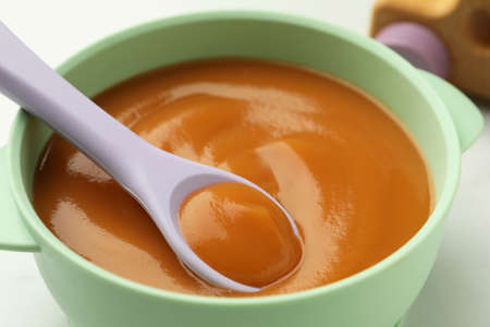 Bowl and spoon with tasty pureed baby food on table, closeupの写真素材