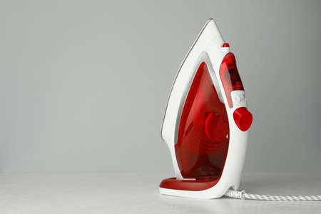 One modern iron on light gray background, space for text. home appliances