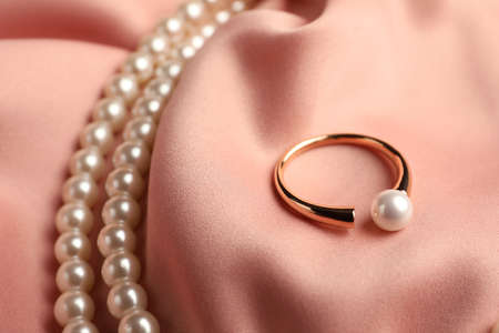 Elegant necklace and ring with pearls on pink silk, closeupの写真素材