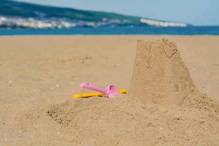 Beautiful sand castle and plastic toys on the beach near the sea, space for textの写真素材