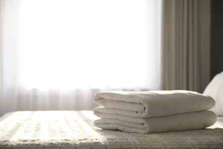 Folded clean blanket on bed in room. Space for textの写真素材