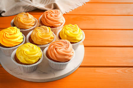 Tasty cupcakes on orange wooden table, space for textの写真素材