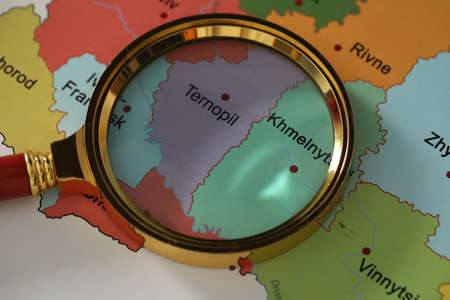Golden magnifying glass above Ternopil and Khmelnytskyi regions on map of Ukraine, closeupの写真素材