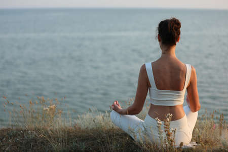 Woman meditating near the sea, back view. Space for textの写真素材