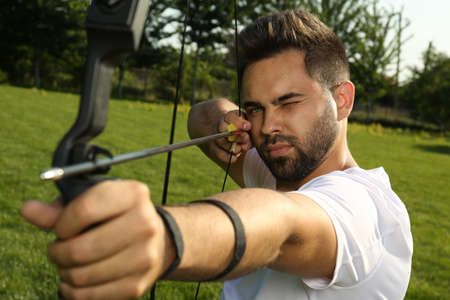 Man with bow and arrow practicing archery in park