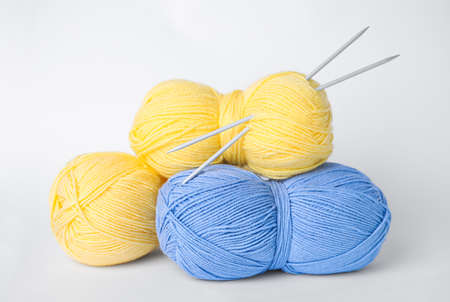 Soft woolen yarns and knitting needles on white backgroundの写真素材