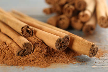 Aromatic cinnamon sticks and powder on gray wooden table, closeup