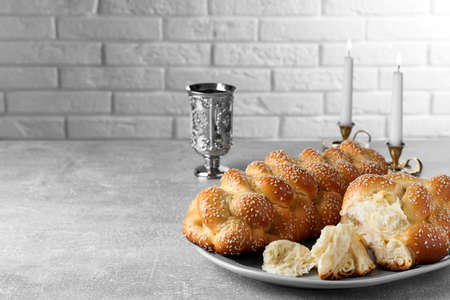Homemade braided bread with sesame seeds and goblet on gray table, space for text. Traditional...