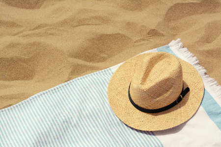 Beach towel with straw hat on sand. Space for textの写真素材