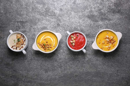 Different tasty cream soups on gray table, flat layの写真素材