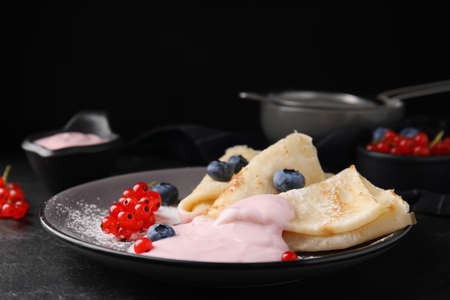 Delicious crepes with natural yogurt, blueberries and red currants on dark gray table. Space for textの写真素材