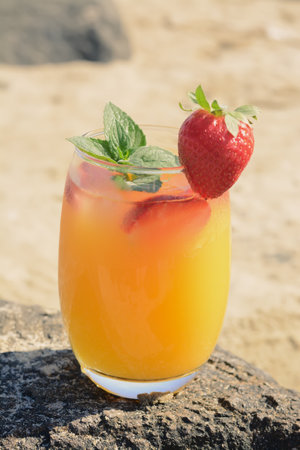 Glass of refreshing drink with strawberry and mint on rock outdoorsの写真素材