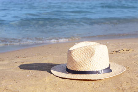Stylish straw hat on sandy beach near the seaの写真素材