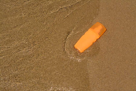 Bottle with sun protection spray near the sea, above view. Space for text