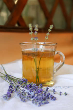 Tasty herbal tea and fresh lavender flowers on white fabricの写真素材