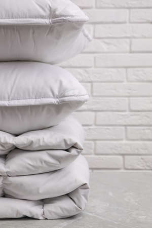 Soft folded blanket and pillows on light gray table, closeup