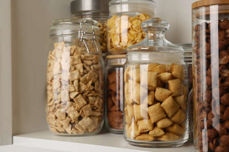 Glass containers with different breakfast cereals on shelf