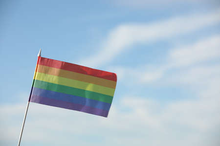 Bright LGBT flag against blue sky with clouds, space for textの写真素材