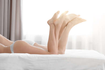 Lovely young couple lying on bed at homeの写真素材