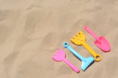 Bright plastic rakes and shovel on sand, space for text. beach toysの写真素材
