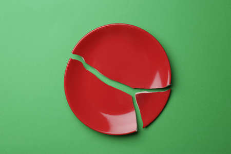 Pieces of broken ceramic plate on green background, flat layの写真素材