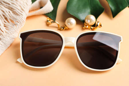 New stylish elegant sunglasses and earrings beautiful on beige background, closeupの写真素材