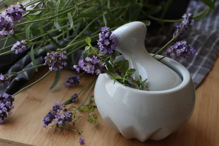 Mortar with fresh lavender flowers, green twigs and pestle on wooden tableの写真素材
