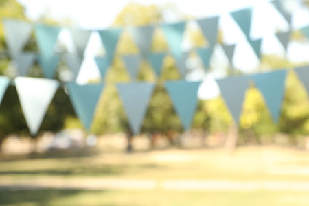 Blurred view of light blue bunting flags in park. party decorの写真素材