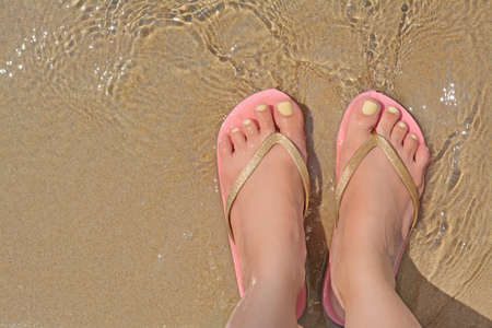 Woman wearing stylish pink flip flops standing in shallow sea water, top view. Space for text