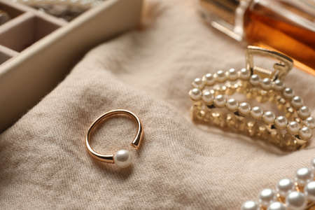 Elegant hair clip and ring with pearls on beige fabric, closeupの写真素材