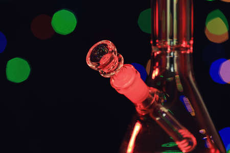 Closeup view of glass bong against blurred lights. smoking device